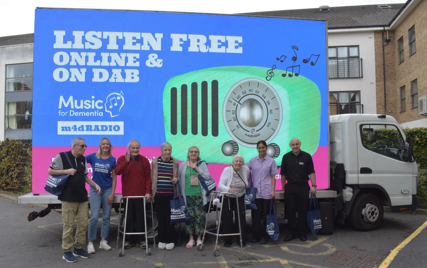Residents and staff standing in front of the Music for Dementia m4dRADIO van, whose side reads Listen free online and on DAB