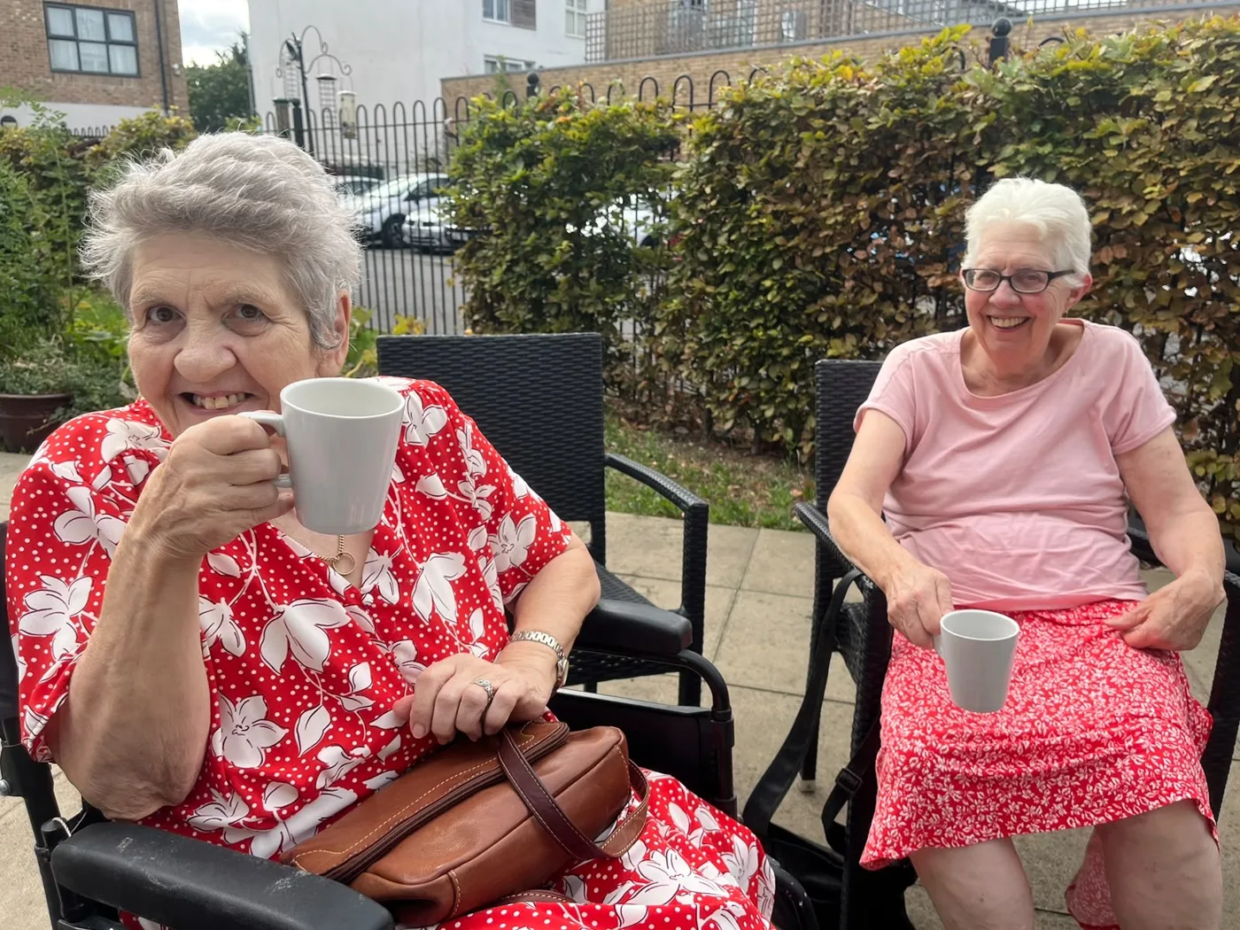 Drayton Village resident Merle and her best friend Jo sitting outside in the garden with mugs of tea