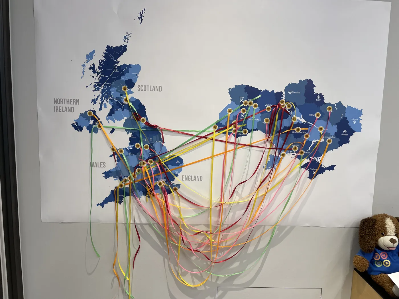 A wall map of the UK and Ukraine with coloured ribbons stretched between pins marking partner schools
