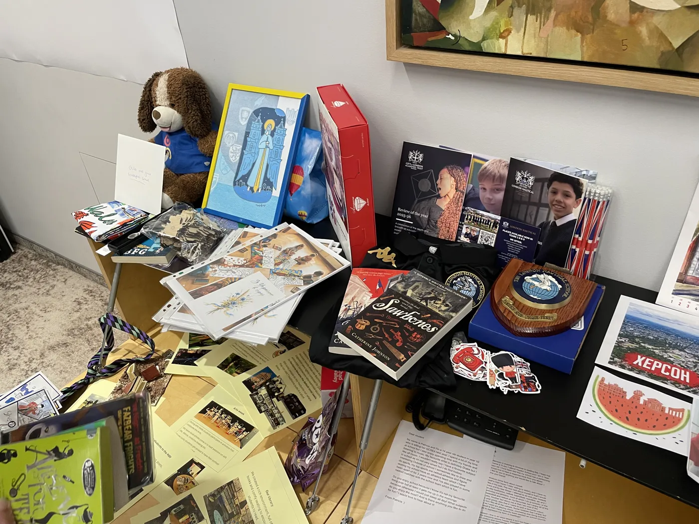 A display table crowded with books, framed pictures, postcards and a teddy bear at the conference