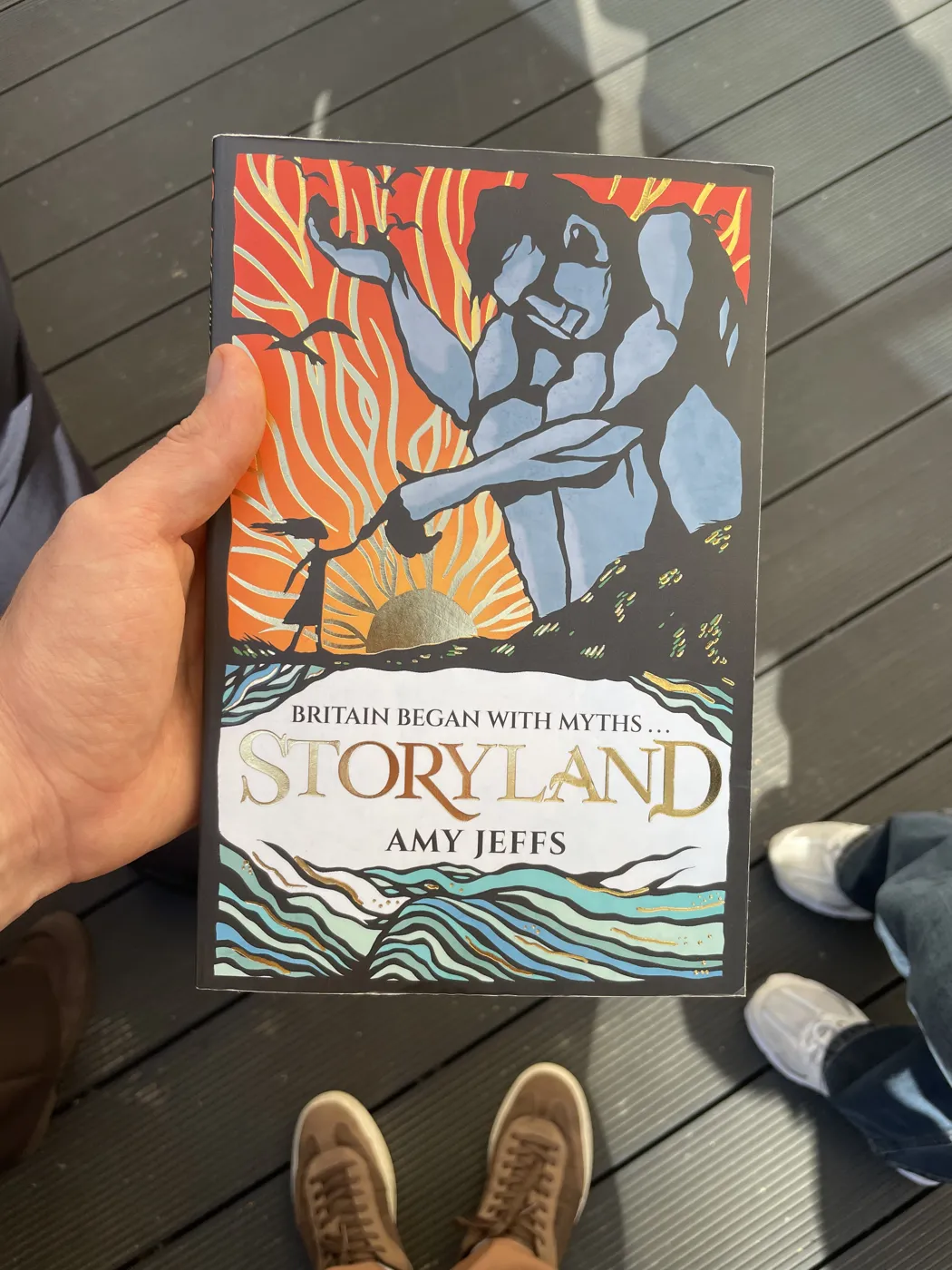A hand holding a copy of Storyland by Amy Jeffs, its cover reading Britain began with myths